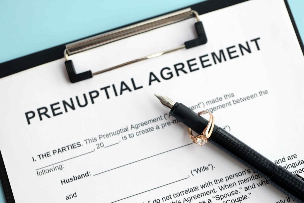 Prenuptial agreement document on clipboard with engagement ring and fountain pen, symbolizing marital contract and asset protection before marriage. Prenuptial agreement document on clipboard with engagement ring and fountain pen, symbolizing marital contract and asset protection before marriage.