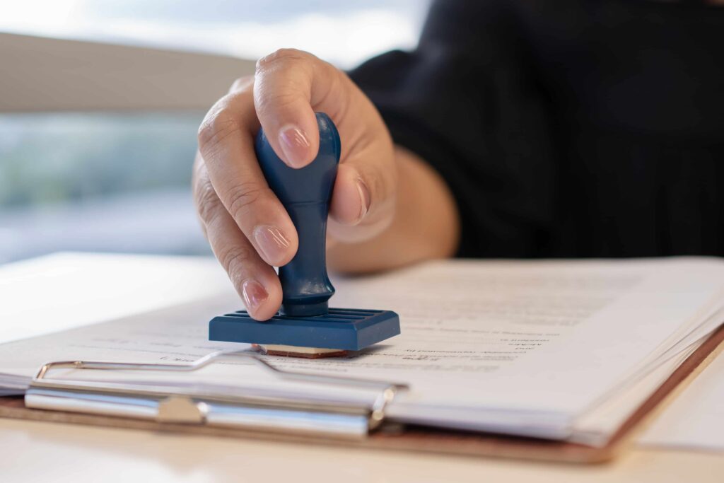 Close-up of hand stamping official document on clipboard, symbolizing legal approval, notarization, or court authorization.