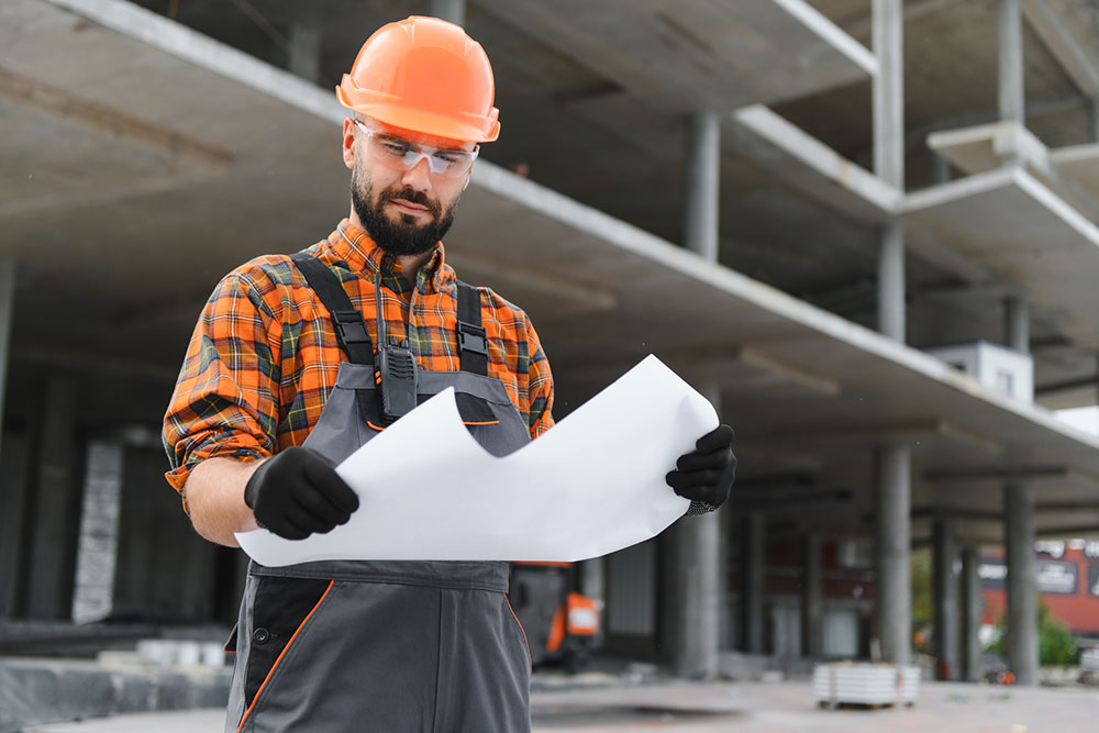 Construction professional reviewing blueprints at a job site, representing expert analysis in a building dispute