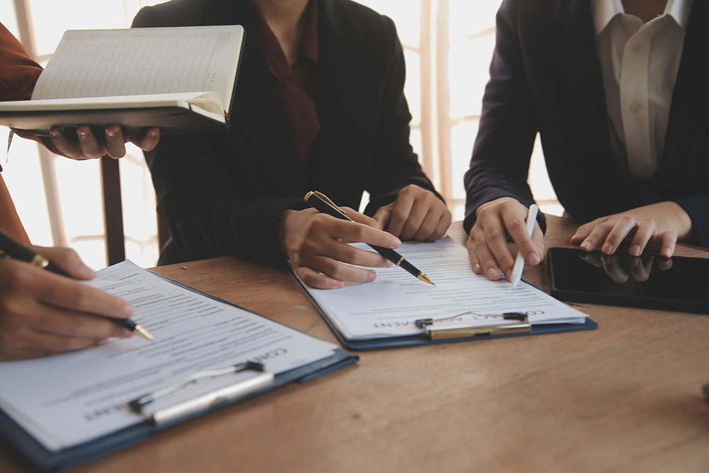 People reviewing contract documents and notes together, representing evaluation of mediation versus arbitration options