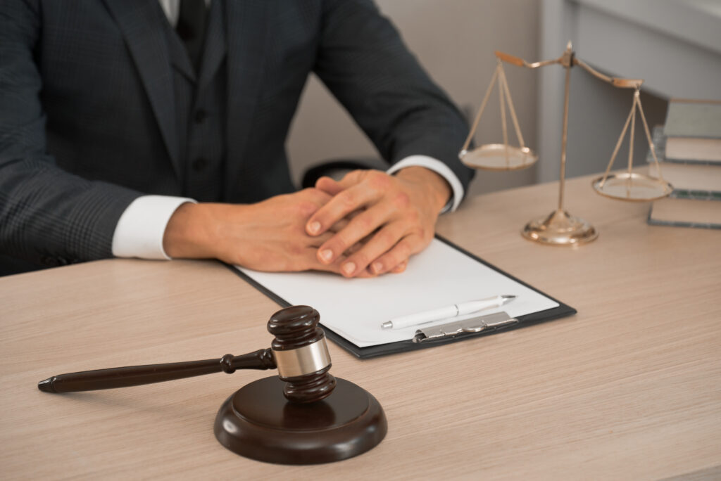 Attorney seated at desk with gavel, scales of justice, and legal documents, representing professional legal consultation and courtroom advocacy.