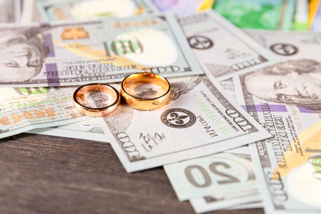 Wedding rings placed on U.S. dollar bills, symbolizing marital assets, divorce settlement, and division of property in family law cases. Wedding rings placed on U.S. dollar bills, symbolizing marital assets, divorce settlement, and division of property in family law cases.