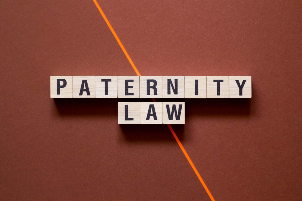 Wooden letter blocks spelling “Paternity Law” on desk, representing legal issues involving fatherhood and child custody rights. Wooden letter blocks spelling “Paternity Law” on desk, representing legal issues involving fatherhood and child custody rights.