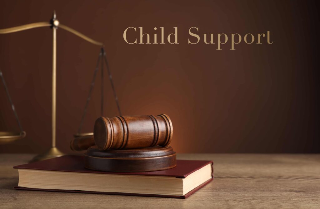 Child support legal concept with judge&rsquo;s gavel on law book and scales of justice in background.