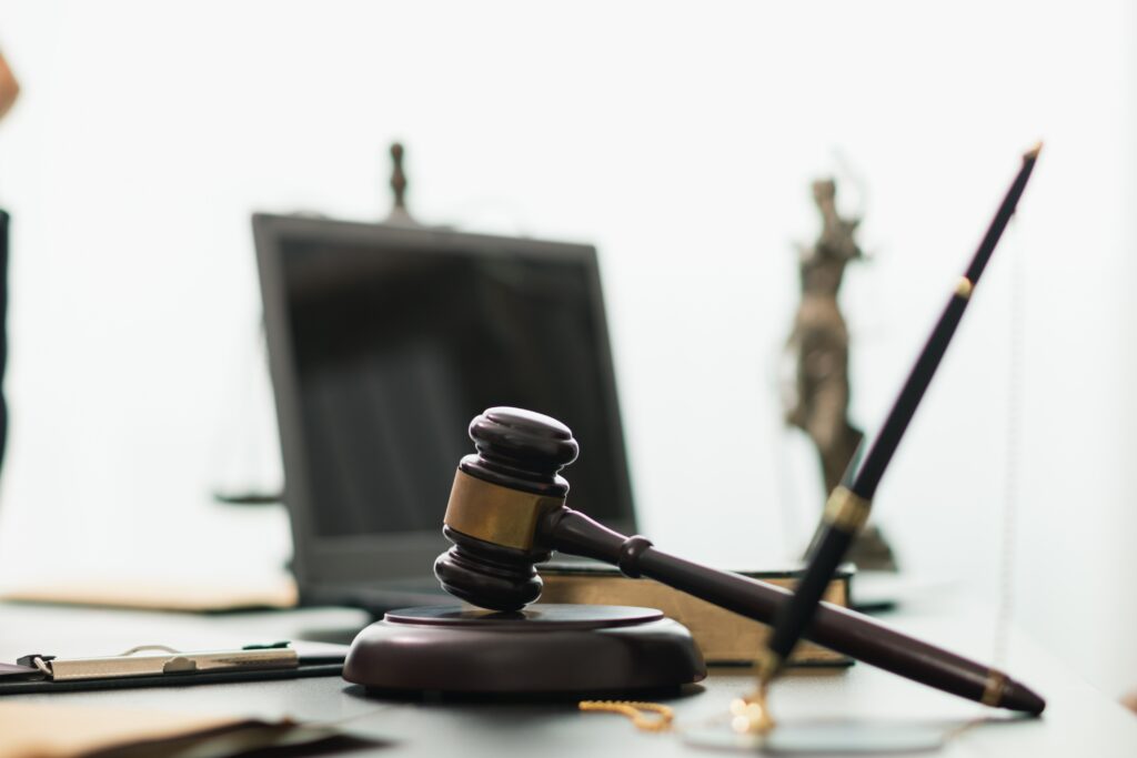 Judge’s gavel on a desk with legal documents and Lady Justice statue in the background, symbolizing law, justice, and legal proceedings. Judge’s gavel on a desk with legal documents and Lady Justice statue in the background, symbolizing law, justice, and legal proceedings.