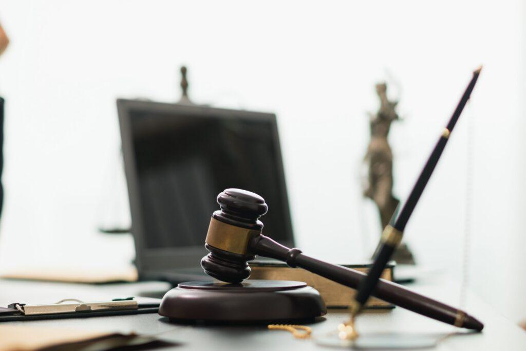 Judge’s gavel on a desk with legal documents and Lady Justice statue in the background, symbolizing law, justice, and legal proceedings. Judge’s gavel on a desk with legal documents and Lady Justice statue in the background, symbolizing law, justice, and legal proceedings.