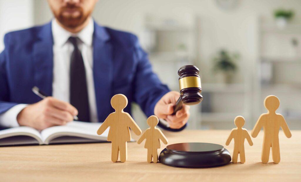 Judge holding gavel behind wooden family figures, representing child custody and family law court proceedings.