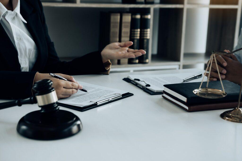Lawyer consulting client at desk with legal documents, gavel, and scales of justice, concept of legal advice and case evaluation