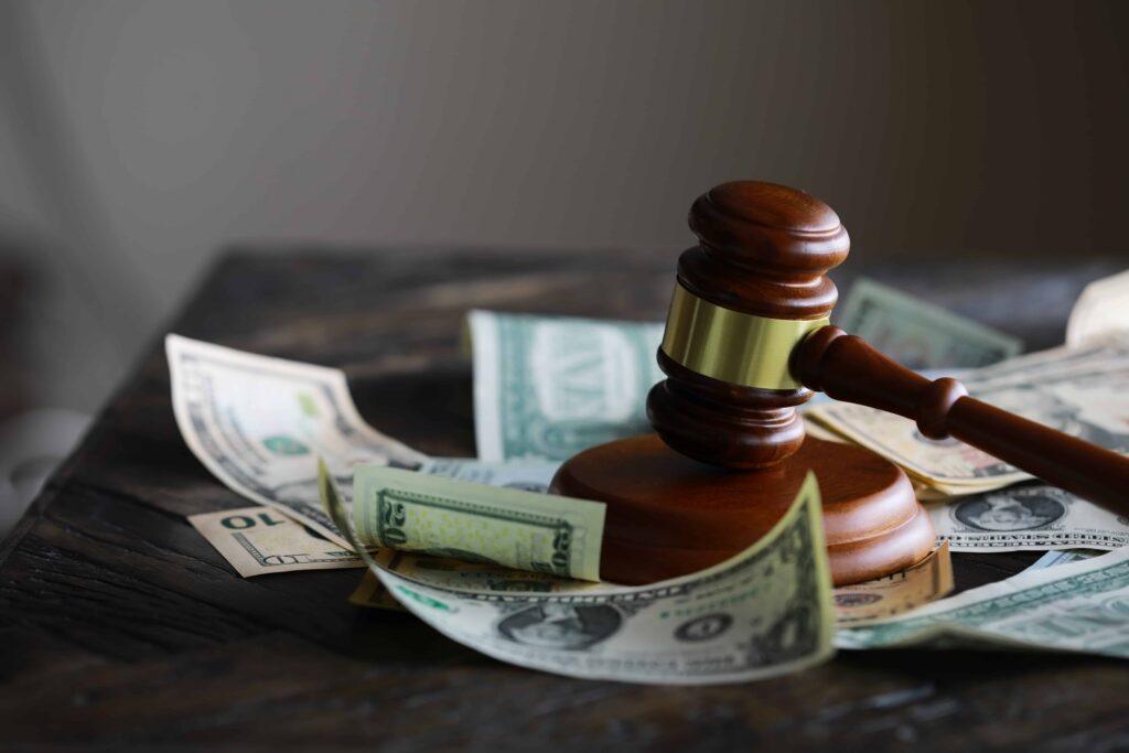 Judge’s gavel resting on US dollar bills, symbolizing legal costs, financial penalties, or lawsuit settlements Judge’s gavel resting on US dollar bills, symbolizing legal costs, financial penalties, or lawsuit settlements