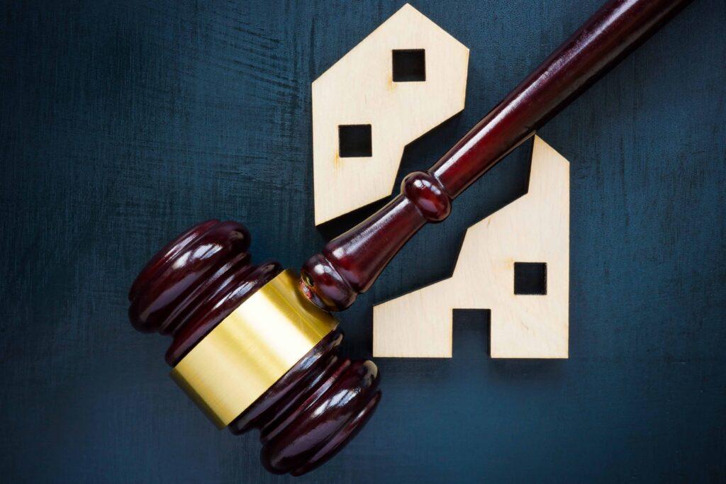 Judge’s gavel next to wooden house icons, representing real estate law, property disputes, or housing litigation Judge’s gavel next to wooden house icons, representing real estate law, property disputes, or housing litigation