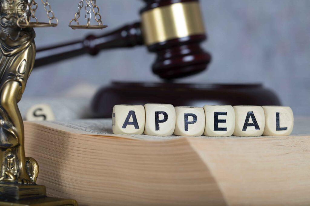 “Appeal” spelled with letter blocks on a law book with gavel and scales of justice, representing legal appeals process and court decisions “Appeal” spelled with letter blocks on a law book with gavel and scales of justice, representing legal appeals process and court decisions
