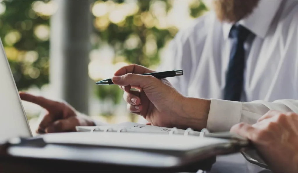 Attorney reviewing legal documents and pointing at laptop during client consultation, representing professional legal advice and case evaluation.