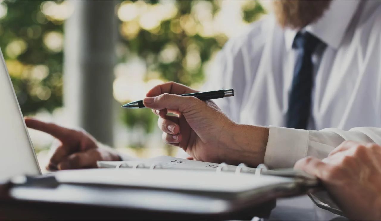 Attorney reviewing legal documents and pointing at laptop during client consultation, representing professional legal advice and case evaluation.