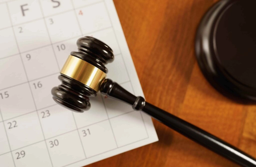 Judge’s gavel resting on a calendar page symbolizing court dates, legal deadlines, or scheduled court hearings.