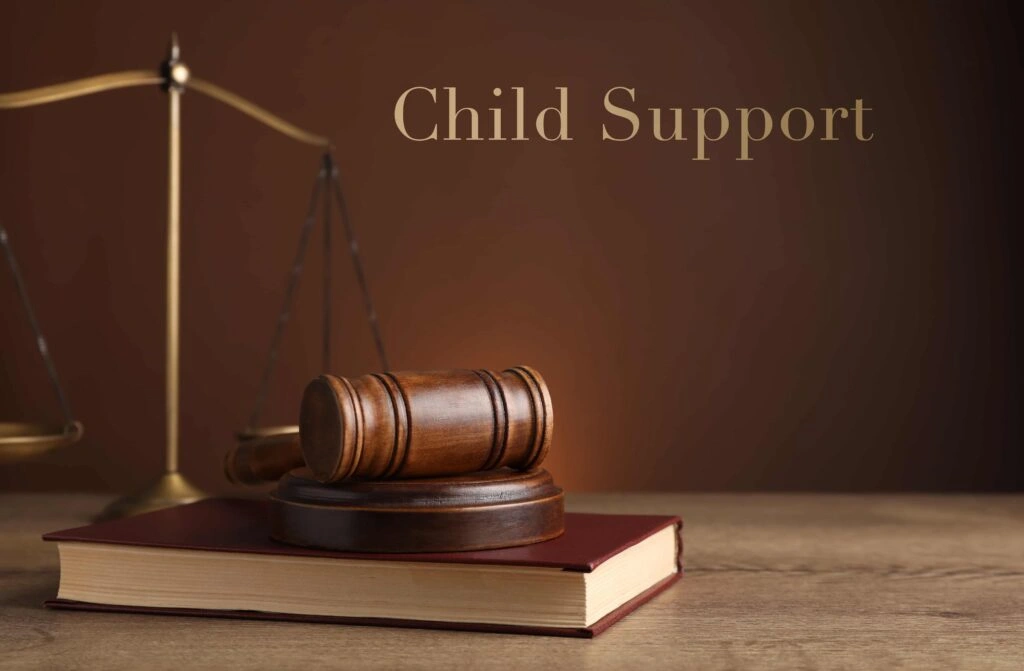 Child support legal concept with judge’s gavel on law book and scales of justice in background.