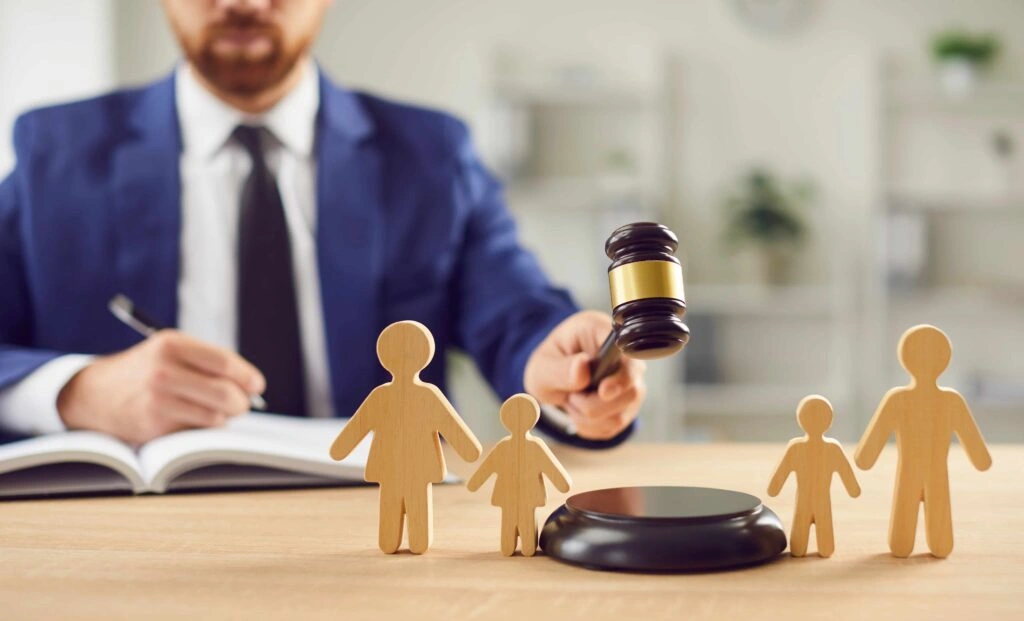 Judge holding gavel behind wooden family figures, representing child custody and family law court proceedings.