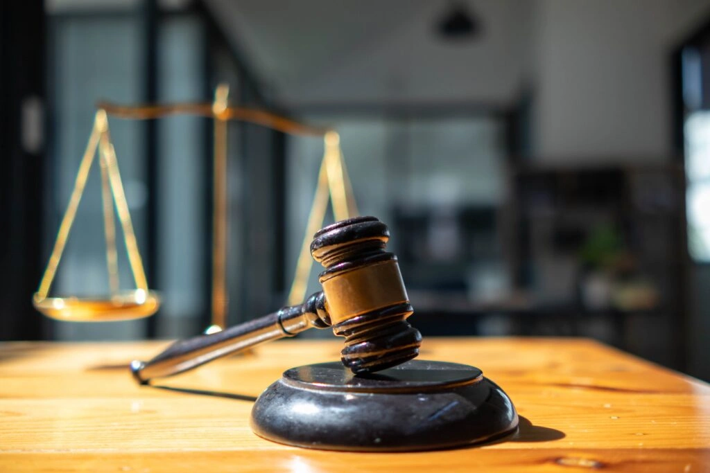 Judge’s gavel on a wooden desk with scales of justice in the background, representing personal injury law, legal claims, and courtroom litigation.
