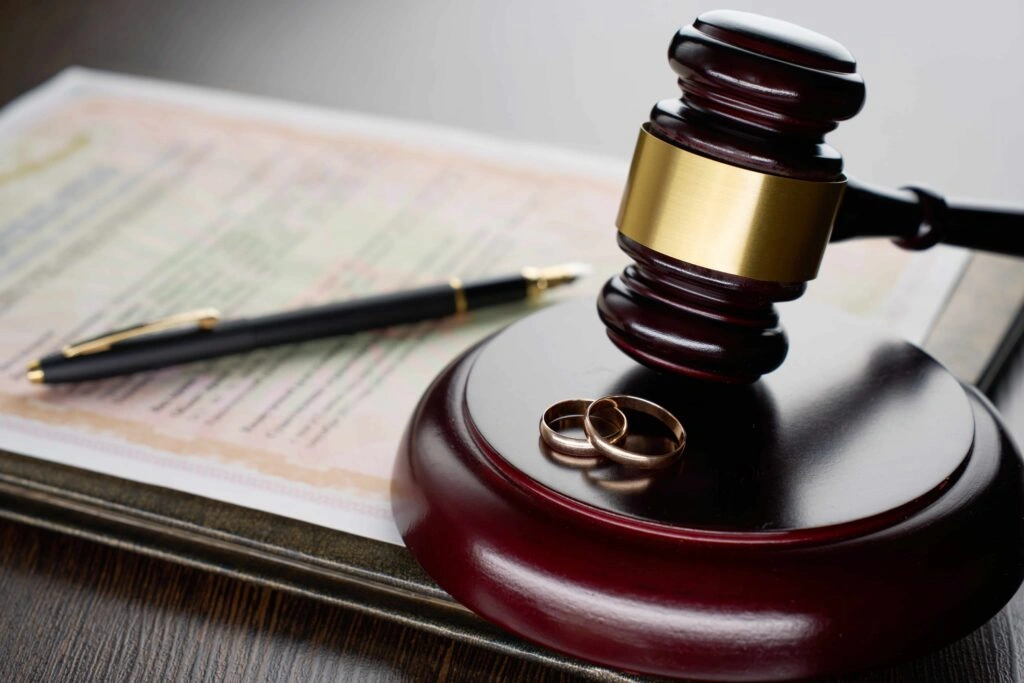 Judge’s gavel and wedding rings on legal document, symbolizing divorce proceedings, marriage dissolution, and family court litigation.