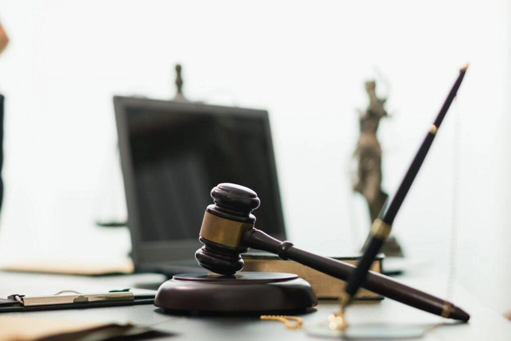 Judge’s gavel on a desk with legal documents and Lady Justice statue in the background, symbolizing law, justice, and legal proceedings.