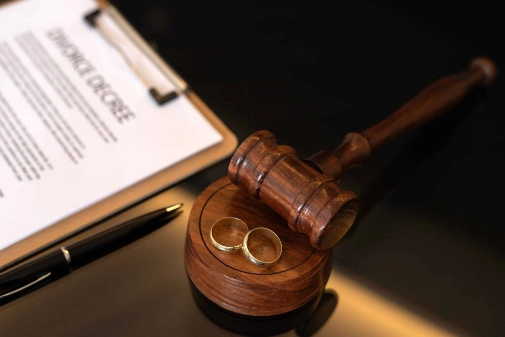 Divorce agreement document with judge gavel and wedding rings on desk, representing family law and divorce proceedings.
